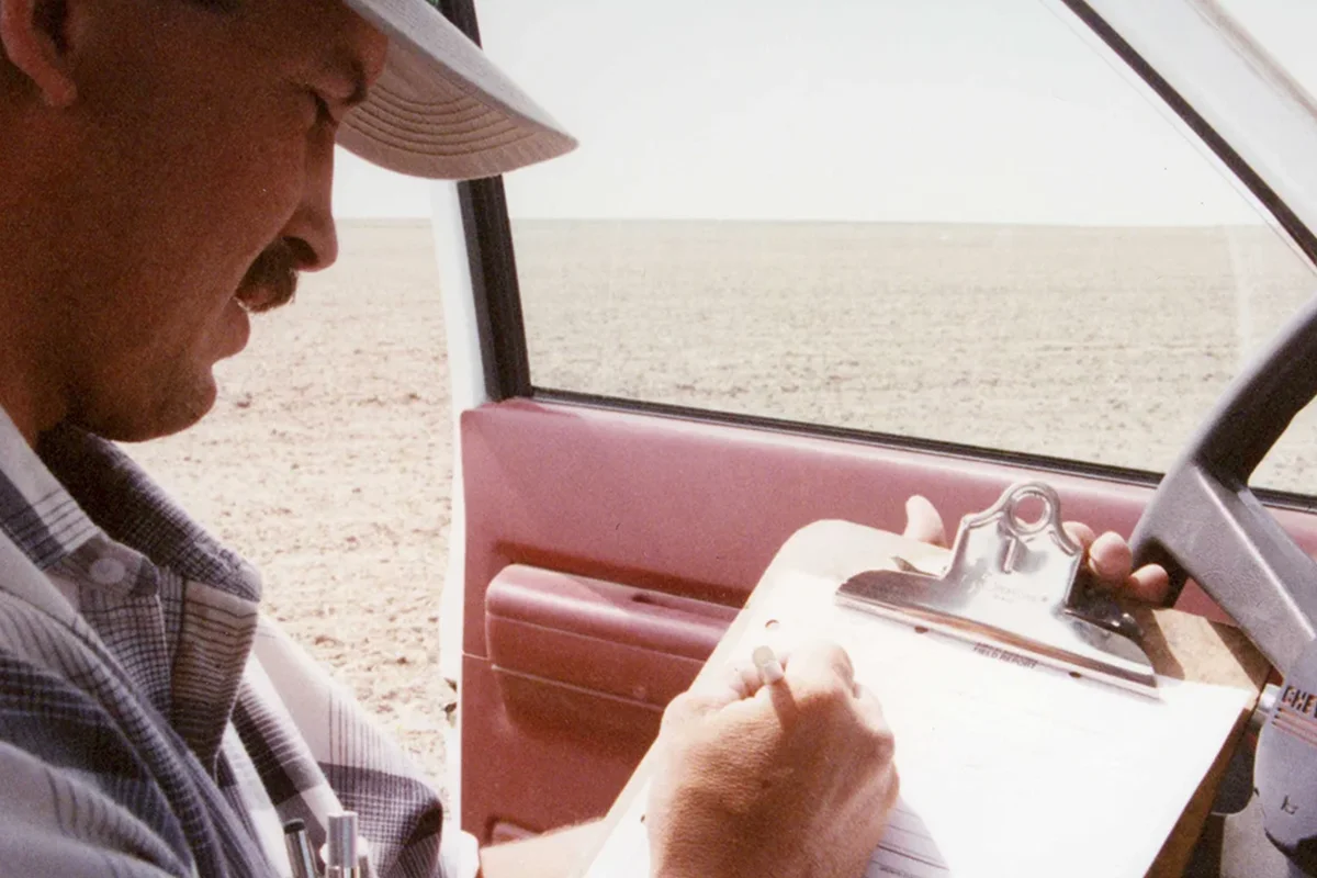 Agronomist writing field notes in truck 2 man sitting in truck taking notes