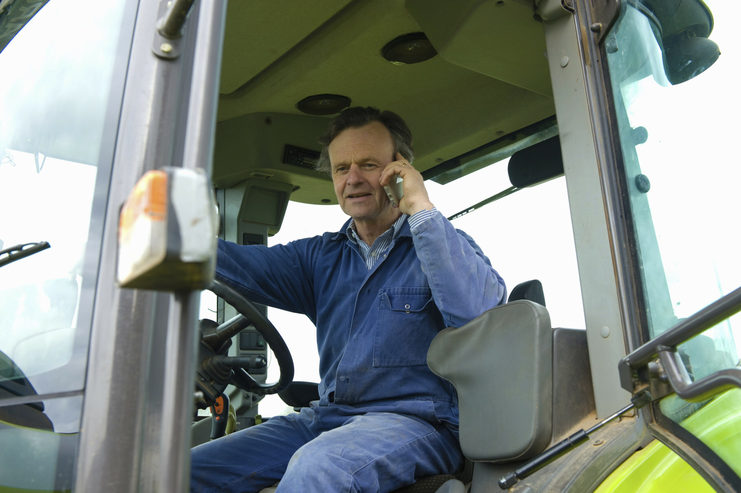 Farmer talking in tractor on smartphone